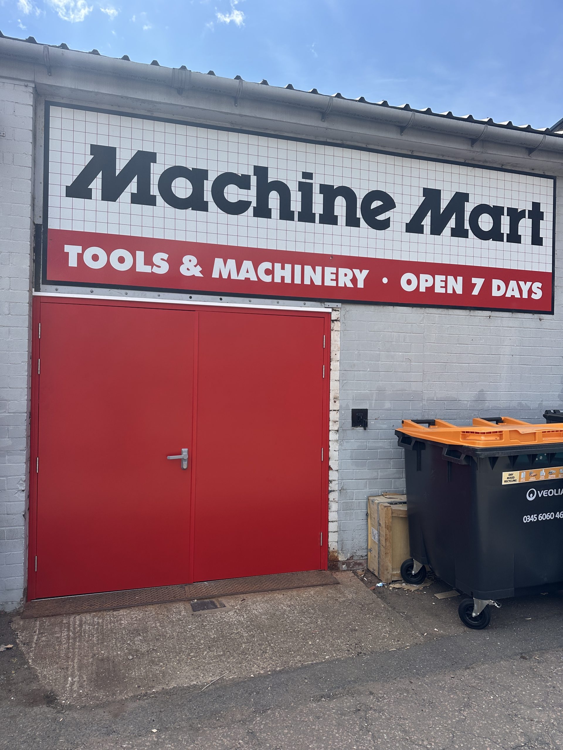Red steel door set installed at the entrance of a commercial retail and machinery building